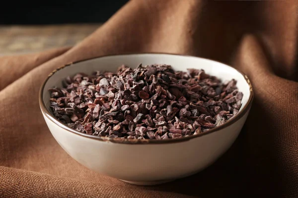 Bowl with cocoa nibs on cloth — Stock Photo, Image