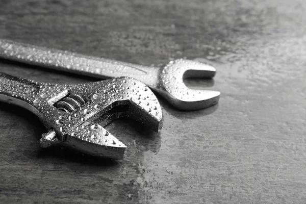 Llave de tornillo y llave inglesa sobre mesa húmeda — Foto de Stock