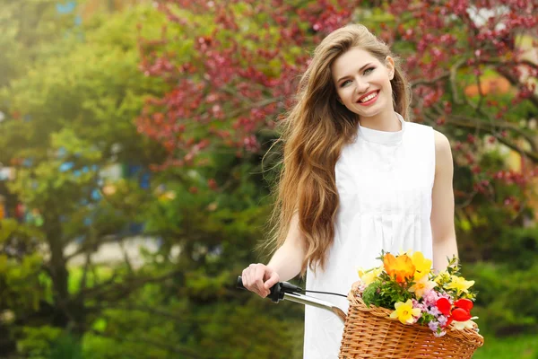Mujer sonriente parada cerca de la bicicleta —  Fotos de Stock