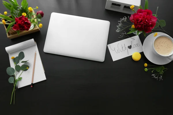 Schöne Blumen und Laptop am Arbeitsplatz — Stockfoto