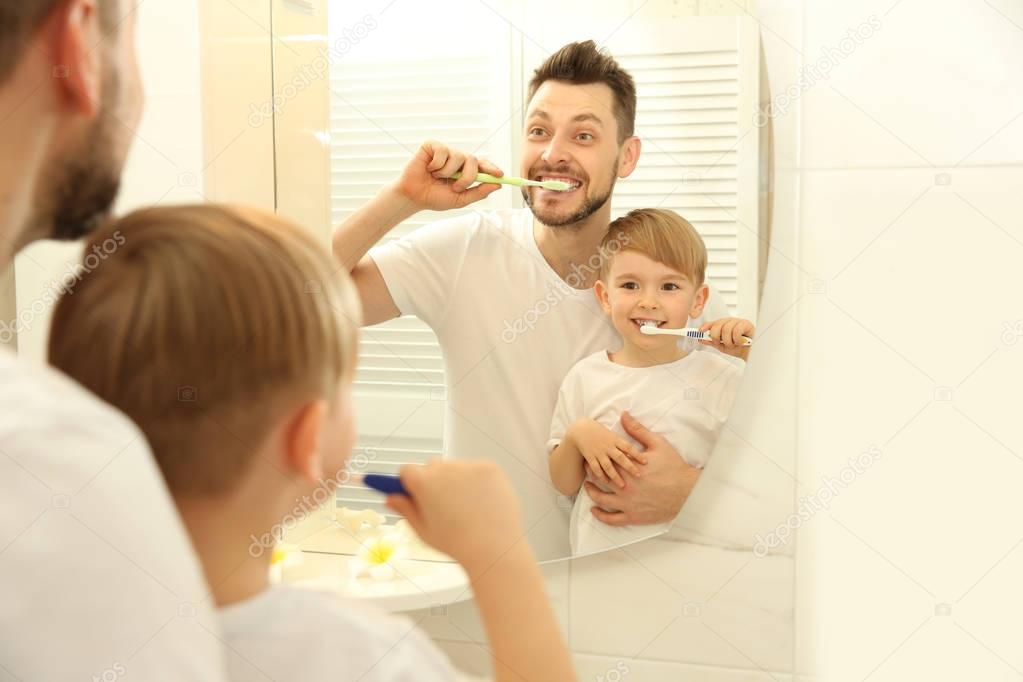 father with son brushing teeth 