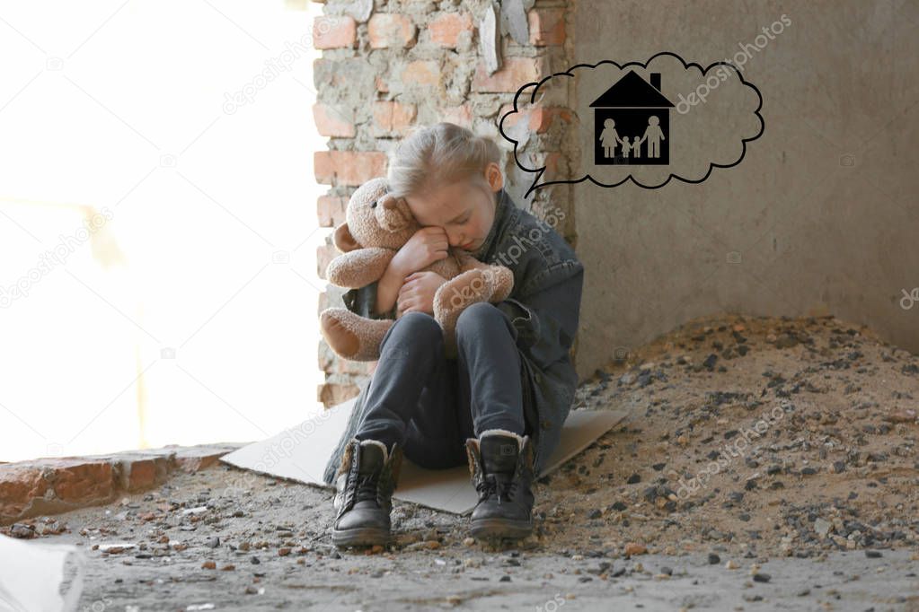 Little girl dreaming about family and home while crying in abandoned building. Poverty concept