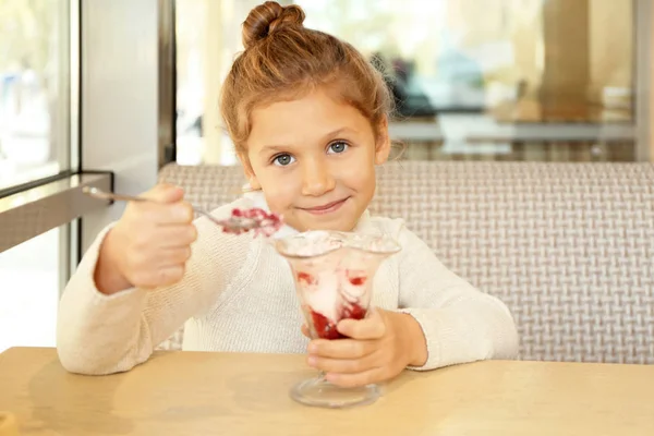 Vicces kis lány eszik fagylaltot, kávézó — Stock Fotó