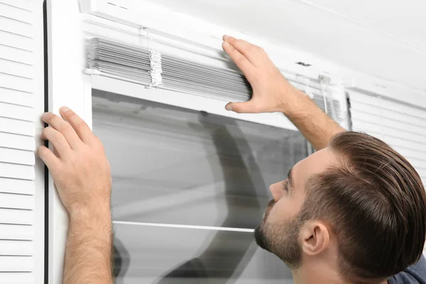 Man installing window blinds