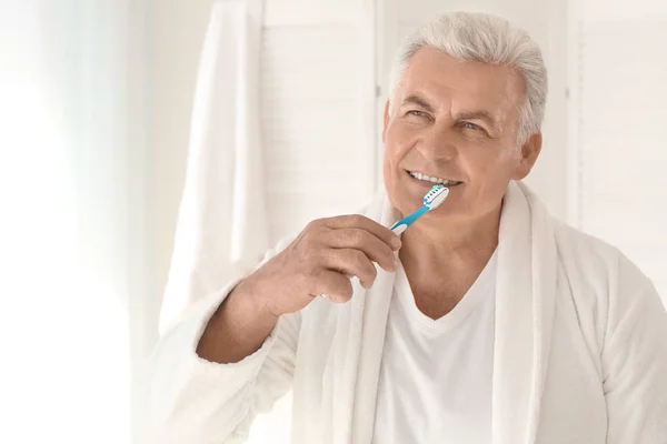 Hombre mayor limpiando dientes en casa — Foto de Stock