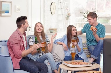 Arkadaş grubu lezzetli pizza ve bira evde Tv izlerken