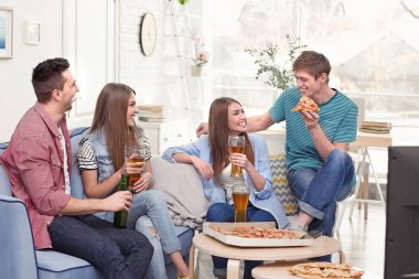 Arkadaş grubu lezzetli pizza ve bira evde Tv izlerken
