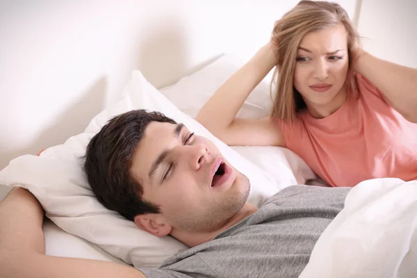 Joven mujer irritada acostada en la cama con el marido roncando en casa —  Fotos de Stock