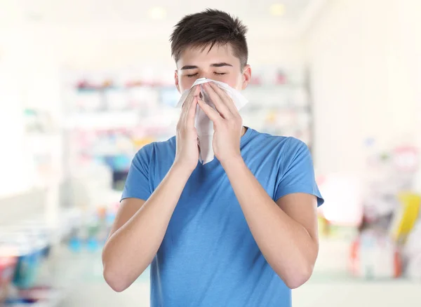 Young man blowing nose in tissue — Stock Photo, Image