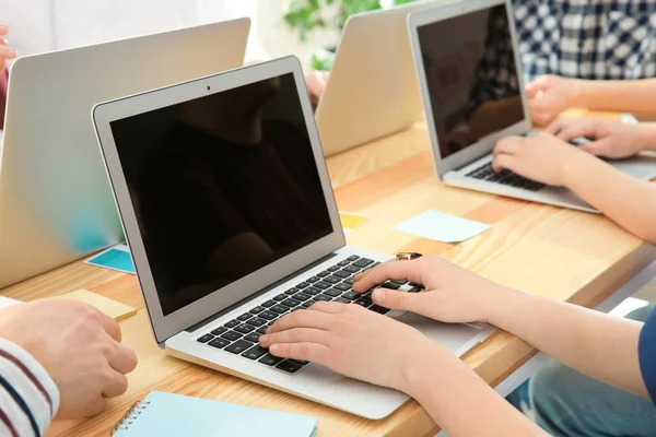 Young people with laptops sitting at table, closeup