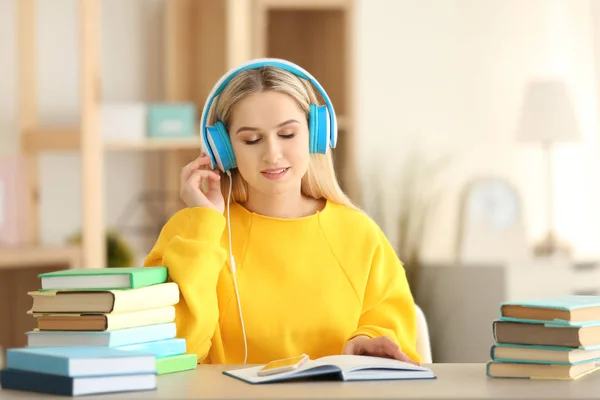 Mujer joven sentada en la mesa y escuchando audiolibros —  Fotos de Stock