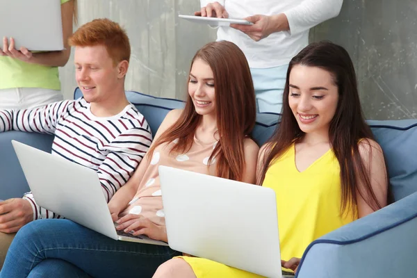 Jeunes avec des ordinateurs portables assis sur le canapé — Photo