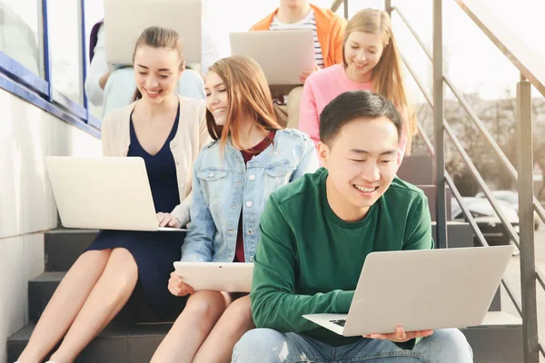 Young people with gadgets sitting on stairs outdoor — Stock Photo, Image