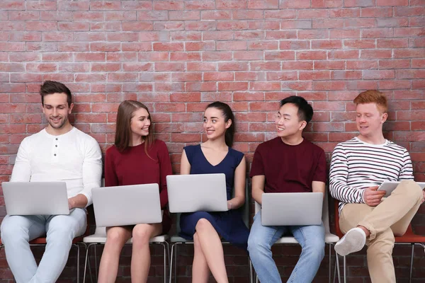 Junge Leute mit Gadgets sitzen auf Stühlen — Stockfoto