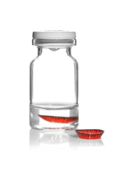 Glass bottle with red contact lenses — Stock Photo, Image