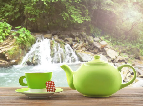 Cup of tea with pot and waterfall — Stock Photo, Image