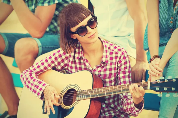 Beautiful girl playing guitar with friends, outdoor — Stock Photo, Image