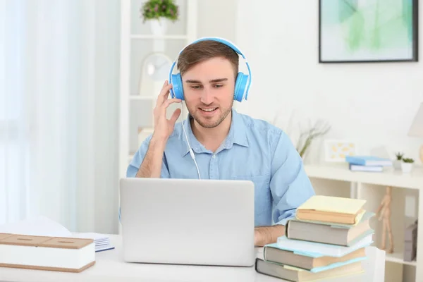 Concepto de audiolibro. Joven guapo con auriculares y libro — Foto de Stock