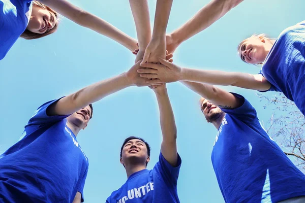 Equipo de voluntarios poniendo sus manos juntas como símbolo de unidad, vista inferior —  Fotos de Stock