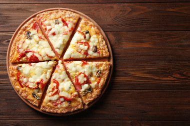 Lezzetli ev yapımı pizza ahşap masanın üzerine dilimlenmiş.