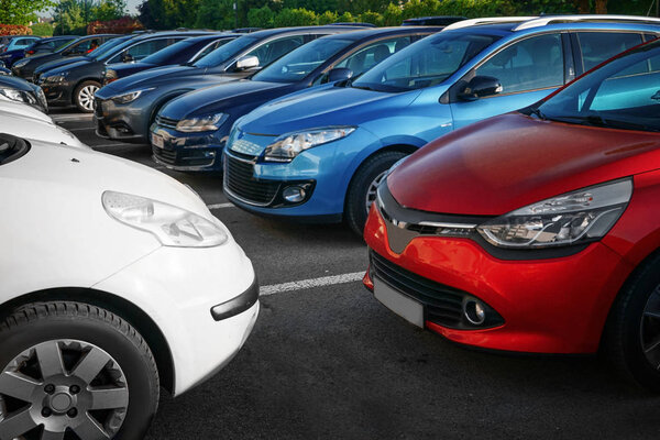 Row of modern cars in parking lots on sunny day