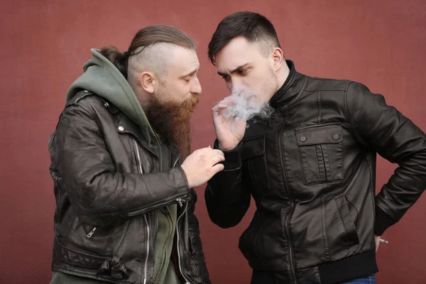 Двое мужчин курят травку на открытом воздухе на цветном фоне — стоковое фото