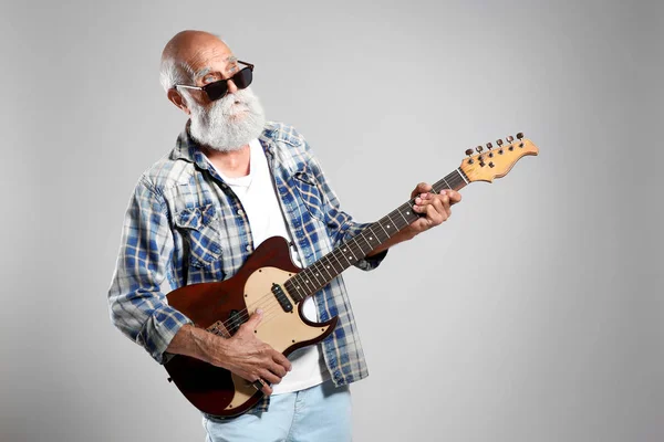 Senior man met gitaar op grijs muur achtergrond — Stockfoto