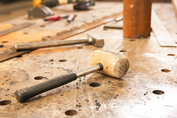 Mallet for metalworking on perforated table — Stock Photo, Image