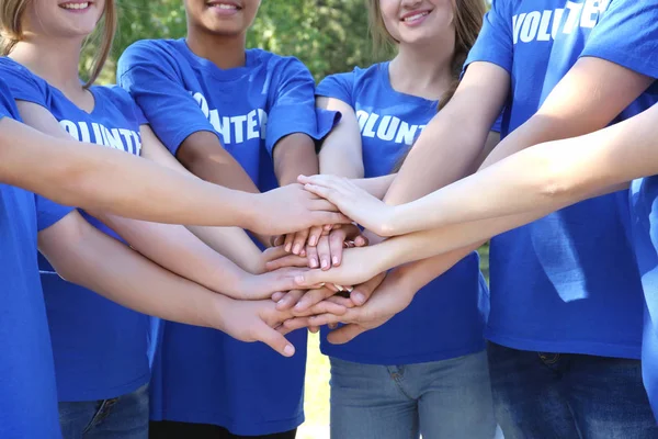 Young people putting hands together outdoors. Volunteer concept — Stock Photo, Image