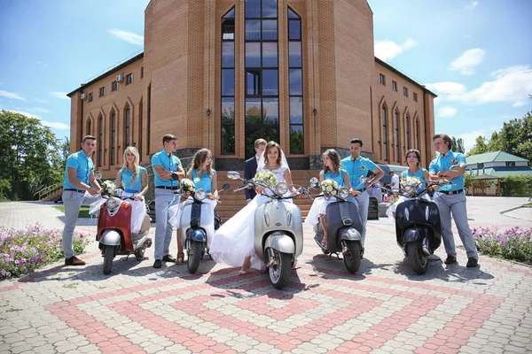 Newlyweds, bridesmaids and best men with scooters