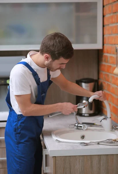 Fontanero guapo reemplazando el grifo en la cocina —  Fotos de Stock