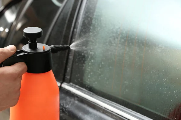 Operaio spruzzando acqua sulla finestra — Foto Stock