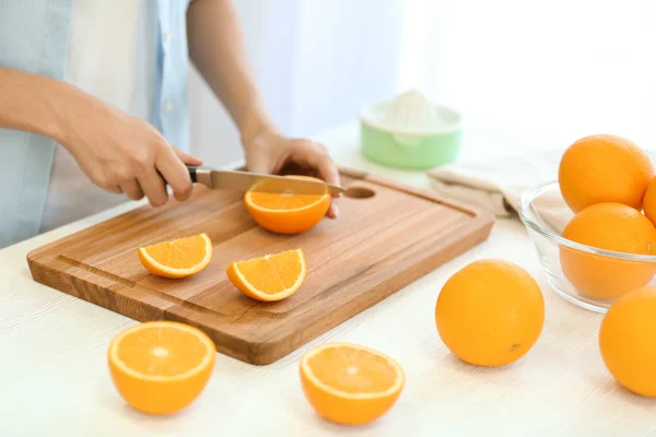 Mãos femininas cortando laranja na cozinha — Fotografia de Stock