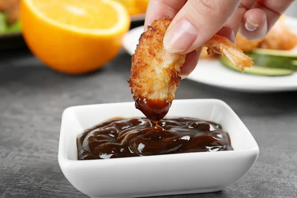 Hand dipping coconut shrimp in sauce — Stock Photo, Image