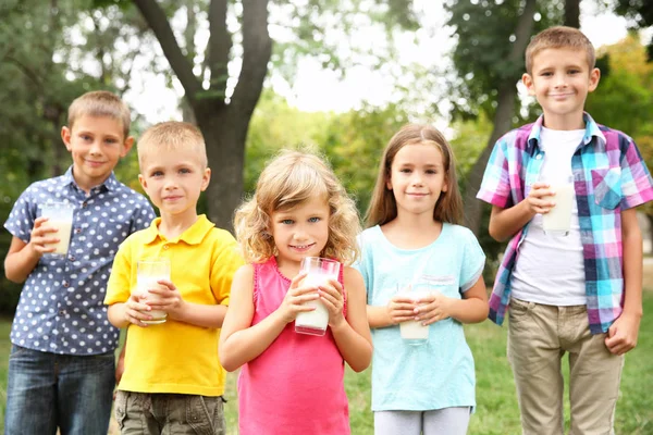 Милые дети с стаканами молока в парке — стоковое фото