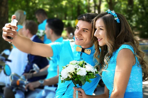 Beautiful bridesmaid and best man taking selfie in park