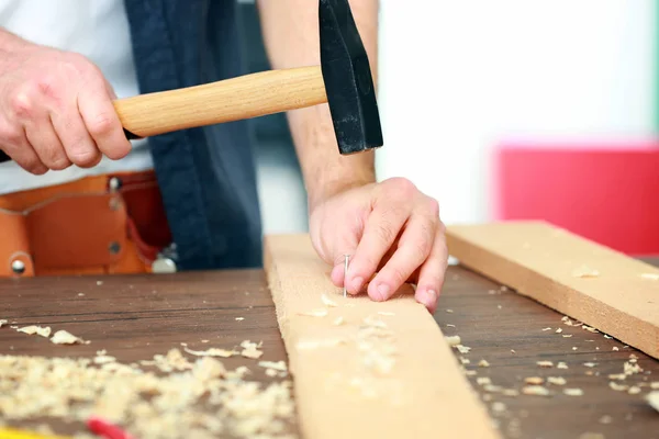 Tischler schlägt Nagel in Holzbrett — Stockfoto