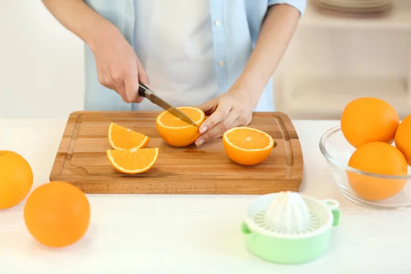 Hembra manos corte naranja en la cocina — Foto de Stock