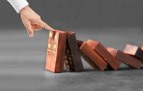 Man försöker stoppa fallande dominobrickor — Stockfoto