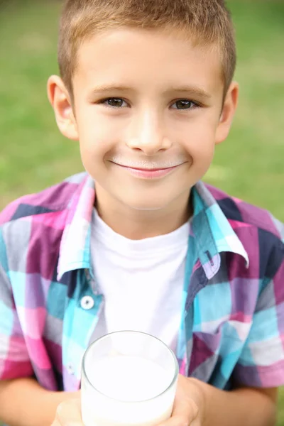 Portret ładny chłopczyk z szklankę mleka, na zewnątrz — Zdjęcie stockowe