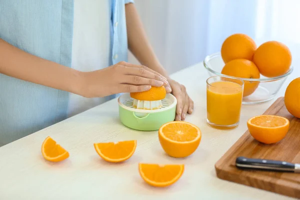 Mãos femininas fazendo suco de laranja — Fotografia de Stock