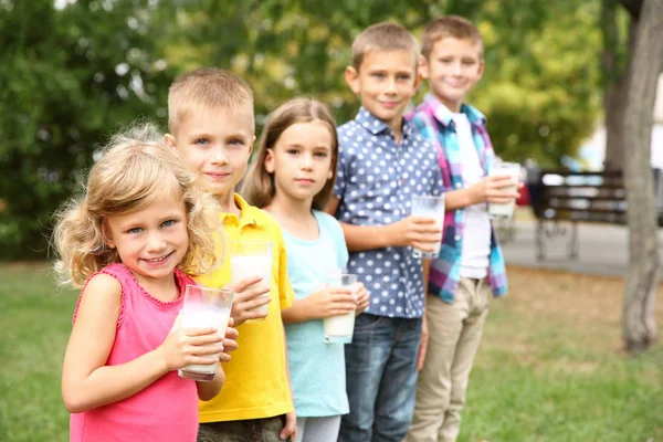 Cute children with glasses of milk in the park — Stock Photo, Image