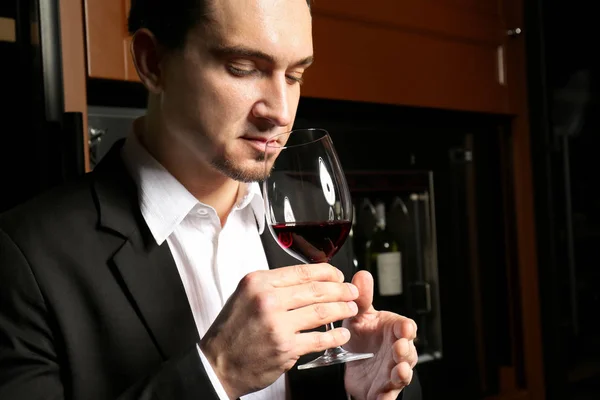 Homem com copo de vinho tinto na adega moderna — Fotografia de Stock