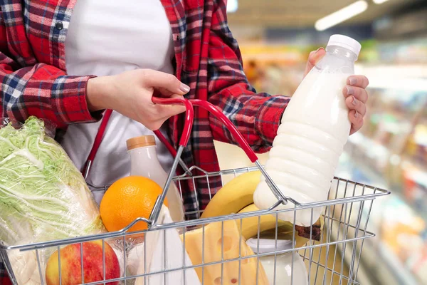 Frau legt Flasche Milch in Korb — Stockfoto