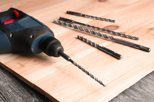 Boor, bijlagen en houten plank op tafel in timmerman werkplaats, close-up — Stockfoto