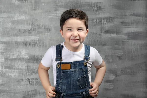 Schattige kleine jongen in de buurt van grijze muur — Stockfoto