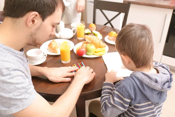 Jovem com filho desenho na mesa da cozinha — Fotografia de Stock