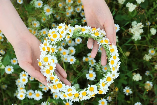 Vrouwelijke handen met mooie kamille krans — Stockfoto