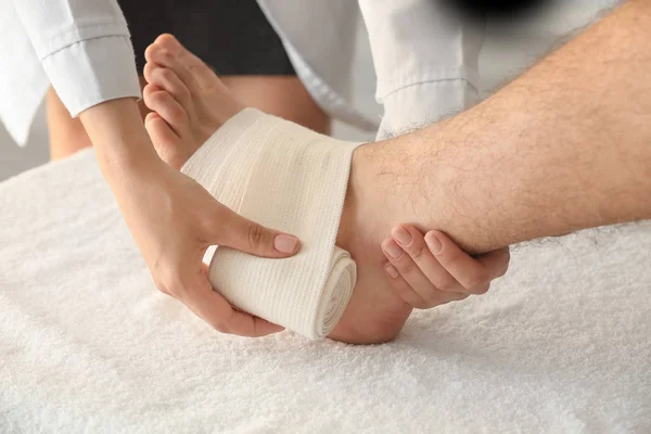 医師のクリニックは、クローズ アップで患者の足の上に包帯を適用します。 — ストック写真