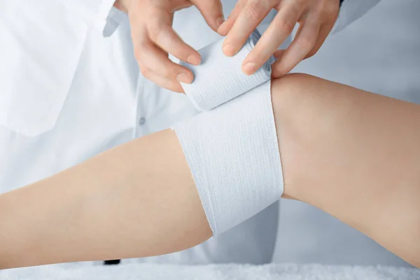 Médico aplicando bandagem na perna do paciente na clínica, close-up — Fotografia de Stock